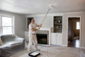 Peintre amateur appliquant de la peinture blanche au rouleau sur un plafond avec une perche télescopique