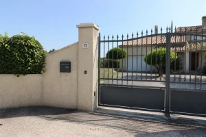 Portail et mur d'entrée d'une maison avec une marque discrète près de la boîte aux lettres